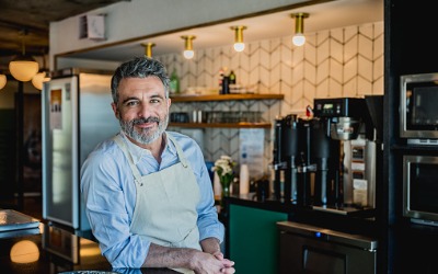 smiling male barista ready to prepare drink in coffee bar